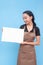 A young asian female waitress or barista holding a blank white signage. Wearing a brown apron and black shirt