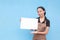 A young asian female waitress or barista holding a blank white signage. Wearing a brown apron and black shirt