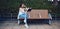 Young Asian focused brunette reading book and sitting on bench