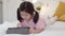 Young Asian girl drawing at home. Asia japanese woman child kid relax rest fun happy using tablet draw cartoon before sleep lying