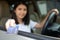 Young Asian girl driving car hand holding credit card payment for gas. Woman car owner paying fuel pump with credit card