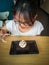 A young asian girl enjoying Brownie with vanilla ice cream served on a plate at a restaurant