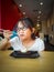 A young asian girl enjoying Brownie with vanilla ice cream served on a plate at a restaurant