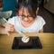 A young asian girl enjoying Brownie with vanilla ice cream served on a plate at a restaurant