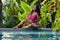 Young asian girl in pink bikini posing in swimming pool