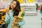 Young Asian girl shopping in a supermarket. Woman buys fruit and dairy product.