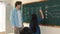 Young asian girl writing math formula at blackboard while standing. Pedagogy.