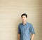 Young asian handsome man who is wearing a blue shirt casual wear is standing in front of wooden wall in office  morning time.