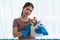 Young Asian housewife wearing gloves and holding basket with cleaners and brushes, cleaning and washing concept