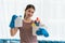 Young Asian housewife wearing gloves and holding basket with cleaners and brushes, cleaning and washing concept