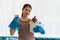 Young Asian housewife wearing gloves and holding basket with cleaners and brushes, cleaning and washing concept