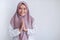 Young Asian Islam woman wearing headscarf gives greeting hands at with a big smile on her face. Indonesian woman on gray