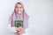 Young Asian Islam woman wearing headscarf is holding holy al quran in hand with smile and happy face. Indonesian woman on gray