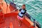 Young Asian lady gives a wink as she stands at the bow of a boat.