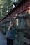 Young Asian lady stand next to ancient pole in Nikko.