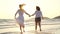 Young Asian lesbian couple running on beach. Beautiful women friends happy relax having fun on beach near sea when sunset in