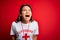 Young asian lifeguard girl wearing t-shirt with red cross using whistle over isolated background angry and mad screaming