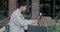 Young Asian male freelancer working with laptop computer sitting at table in modern street cafe