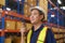 Young asian male worker wearing helmet using talki walki in modern warehouse