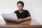 Young Asian man is boring and lazy in the front the laptop. Indonesia Man wear black shirt  grey background