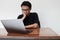 Young Asian man is boring and lazy in the front the laptop. Indonesia Man wear black shirt  grey background