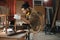 Young Asian man Carpenter uses a tape measure to measure chair on the workbench in woodcraft carpentry workshop.