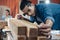 Young Asian man Carpenter uses a tape measure to measure wood on the workbench in woodcraft carpentry workshop.