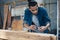 Young Asian man Carpenter uses a tape measure to measure wood on the workbench in woodcraft carpentry workshop.