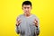 Young Asian man doing angry gesture, annoyed, and emotional, isolated on yellow