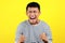 Young Asian man doing angry gesture, annoyed, and emotional, isolated on yellow
