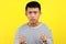 Young Asian man doing angry gesture, annoyed, and emotional, isolated on yellow