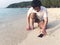 Young Asian man dropping mobile smart phone on tropical sandy beach. Accident and insurance electronic equipment concept