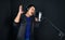 Young asian man with headphones singing in front of black soundproofing wall. Musician producing music in professional recording