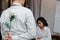 Young Asian man hiding a white rose behind his back for surprise girlfriend in valentines day. Love and romance in office concept.