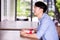 Young Asian man patiently sitting in cafe restaurant and holding a present gift giving to someone special for special occasion.