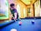 Young Asian man play billiards in the colorful club - Aiming white ball to shot