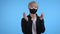 Young asian man in protective mask dancing on blue studio background. Handsome male korean model guy. Party, happiness