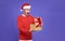 Young asian man in red casual attire wearing Santa hat opening presents box and looking excited and surprise something inside box