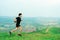 Young Asian man runner, wearing black sportswear, running on a big mountain trail, cool morning, windmills, and sky in the