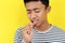 Young Asian man showing ulcer or blister in his mouth at camera, isolated on yellow