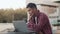 Young asian man sitting in the outdoor cafe with a laptop and discussing with a client working issues on a video call