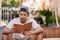 Young Asian man sitting on stairs outside reading a book