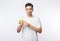 Young asian man in white t-shirt peeling banana and looking to camera isolated on white background.