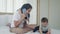 Young asian mother talking phone and playing with baby girl together on the bed, mom and daughter.
