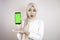 Young Asian Muslim beautiful girl wearing head scarf is shocked showing green screen smartphone