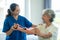 A young Asian nurse at a nursing home takes care of a senior woman. The attending physician provides physical therapy services