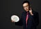 Young asian pharmacist doctor in official suit and glasses holds shows plate of medical pills and holds forefinger up