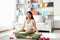 Young asian pregnant woman meditating yoga in lotus position, sitting on yoga mat in living room. Pregnancy mother close eyes and