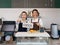 Young asian shopkeeper and  caucasian barista with a smile holds an OPEN sign in front of a coffee shop counter. Morning