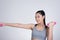 Young asian sporting woman training with dumbbell. Pretty athletic girl making physical exercise against white background. Health